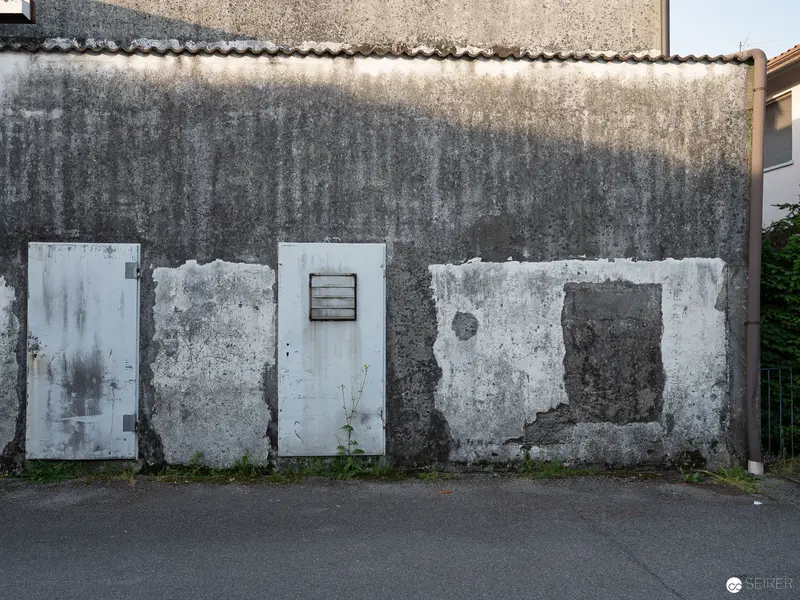 Weathered Concrete Wall with Deteriorating Doors and Architectural Surfaces