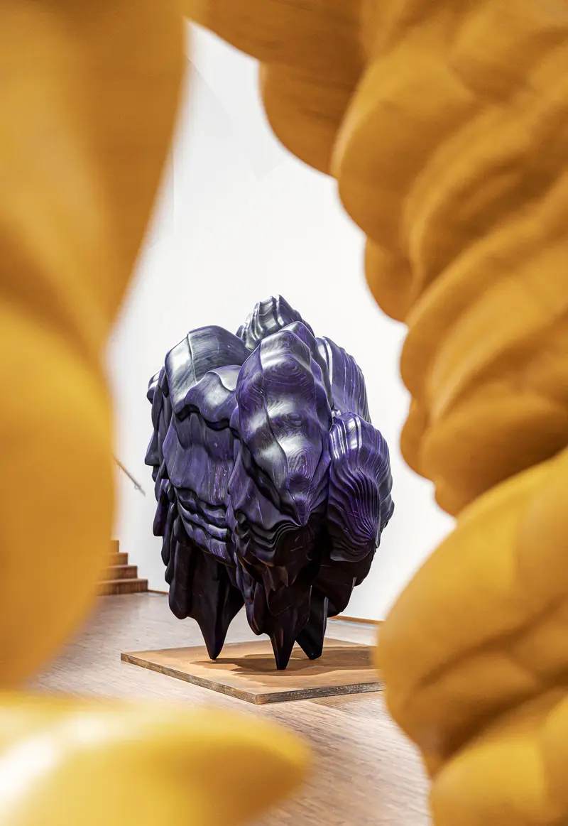 Tony Cragg Sculptural Installation: Dark Organic Form Framed by Golden Folds