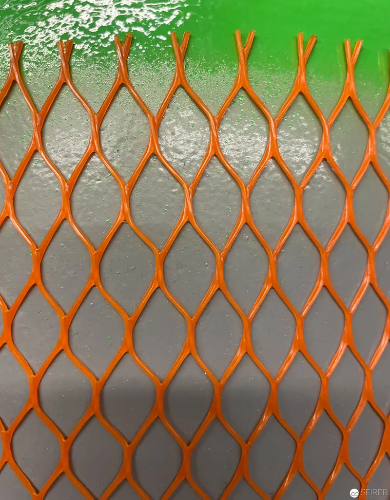 Geometric Orange Metal Mesh Grid Against Green and Gray Background