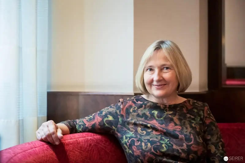 Ute Krause Seated on Red Sofa During Interview with Janett Cernohuby