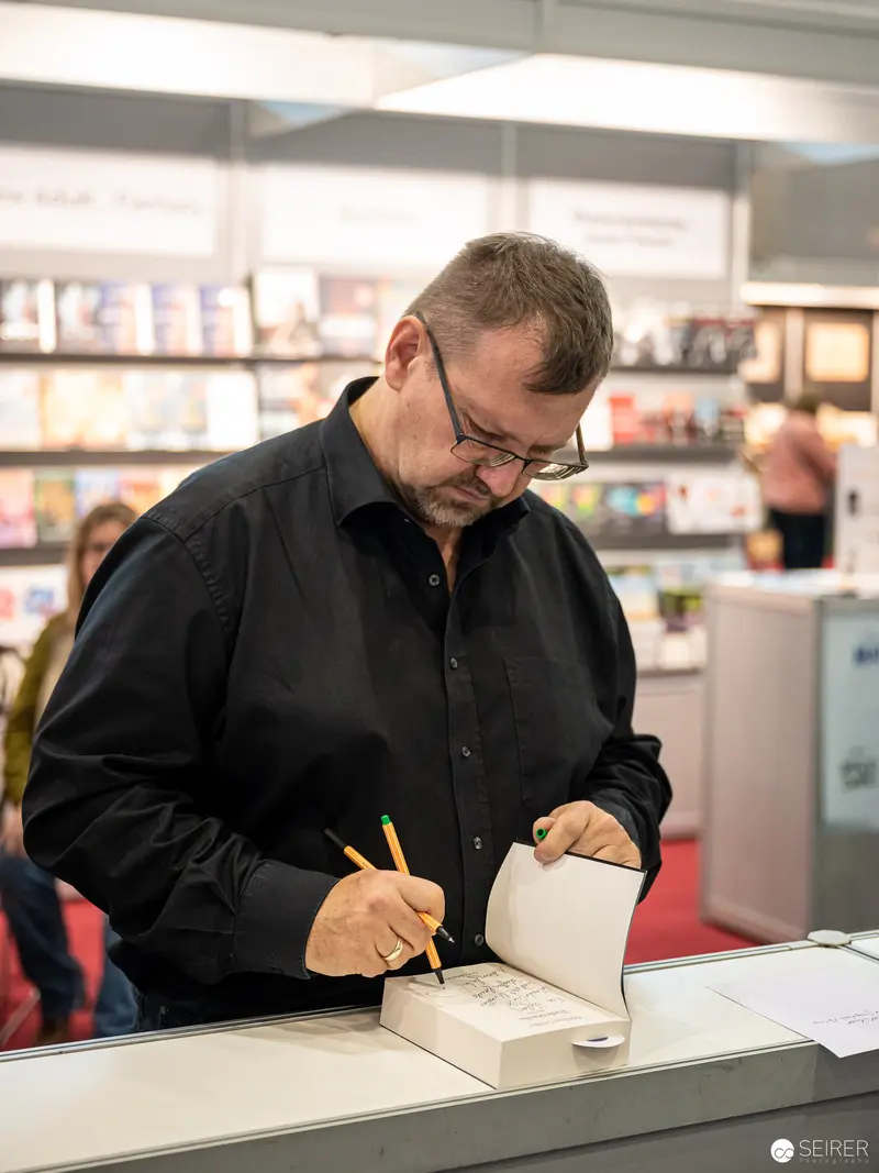 Book Signing at Buch Wien 2022: Author Writing with Concentrated Precision