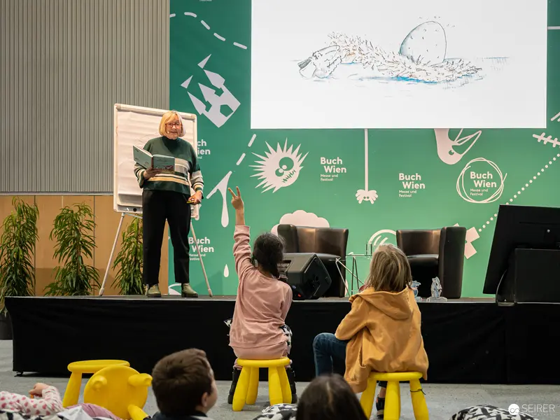 Buch Wien 2022: Author Reading with Children Engaging from Yellow Stools