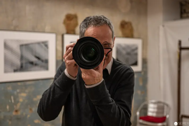 Photographer's Reflective Self-Portrait in Gallery Space with Framed Artwork