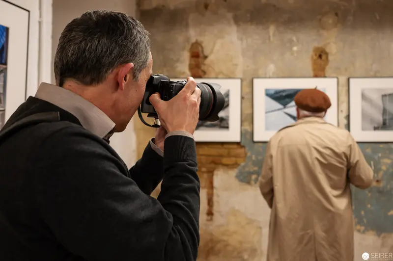 Photographers Documenting Gallery Exhibition with Framed Black and White Images