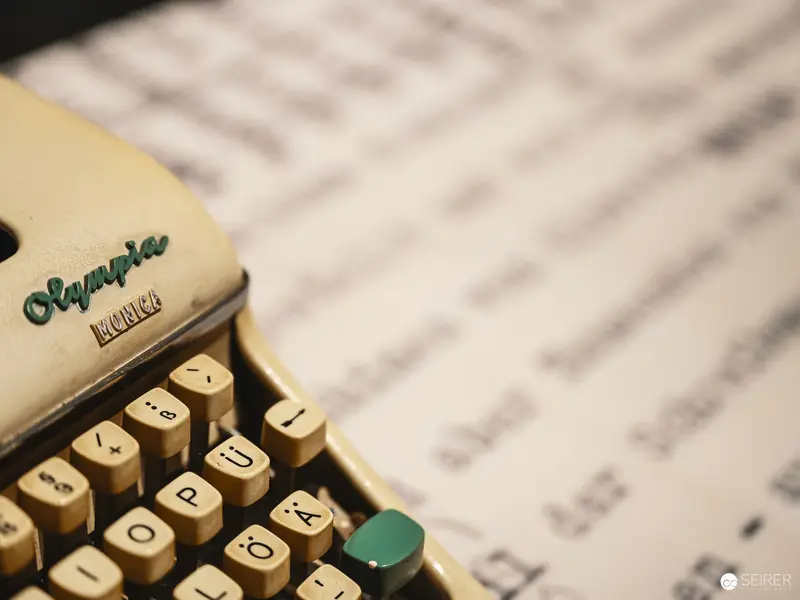 Vintage Olympia Typewriter with Blurred Manuscript Page in Background