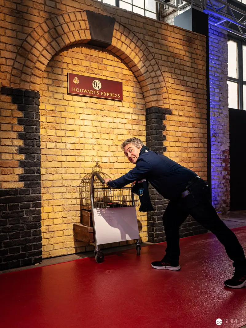 Visitor Recreating Platform 9¾ Entrance at Harry Potter Exhibition, Vienna