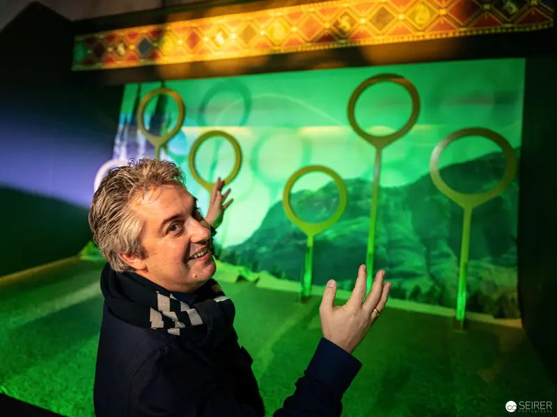 Harry Potter Exhibition in Vienna: Green-Lit Magical Display with Enthusiastic Gesturing Guide