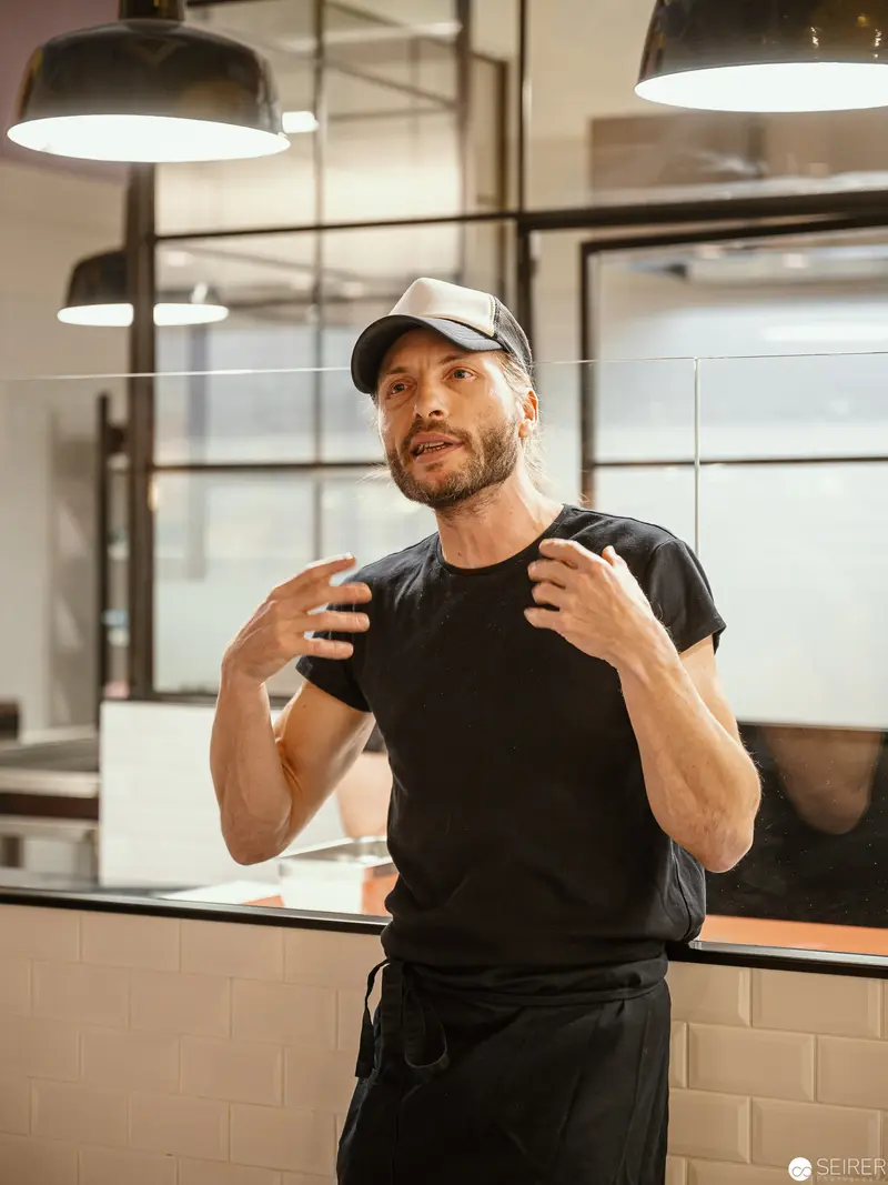 Zuckerlwerkstatt Wien: Artisan in Black Gesturing in Workshop Kitchen