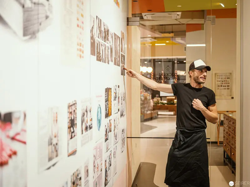 Workshop Storyteller at Zuckerlwerkstatt Wien Pointing to Photographic Archive Wall