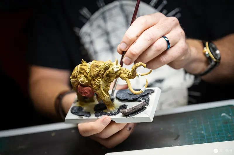 Artisan Hand-Painting Intricate Golden Miniature Fantasy Creature at Workstation