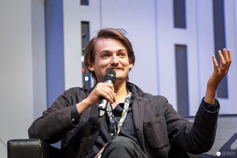 Speaker Gesturing Energetically During Panel Discussion at Vienna ComicCon 2022