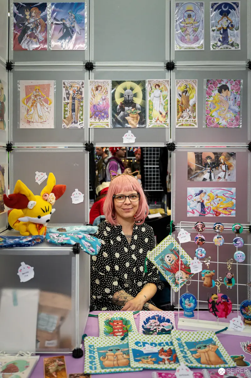 Artist Surrounded by Colorful Comic and Illustration Artwork at Vienna ComicCon