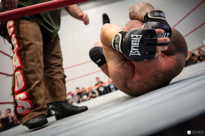 Wrestler in Everlast Gloves Defeated on Canvas at Wrestling Event