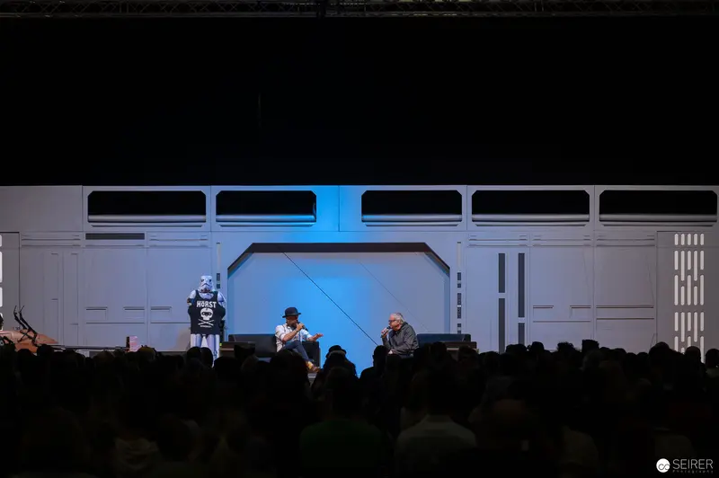 Vienna ComicCon Panel Discussion Under Blue-Tinted Sci-Fi Stage Lighting