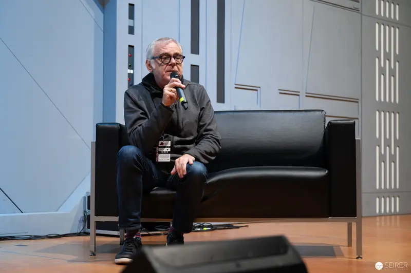 Veteran Speaker at Vienna ComicCon, Seated in Reflective Pose on Black Leather Couch