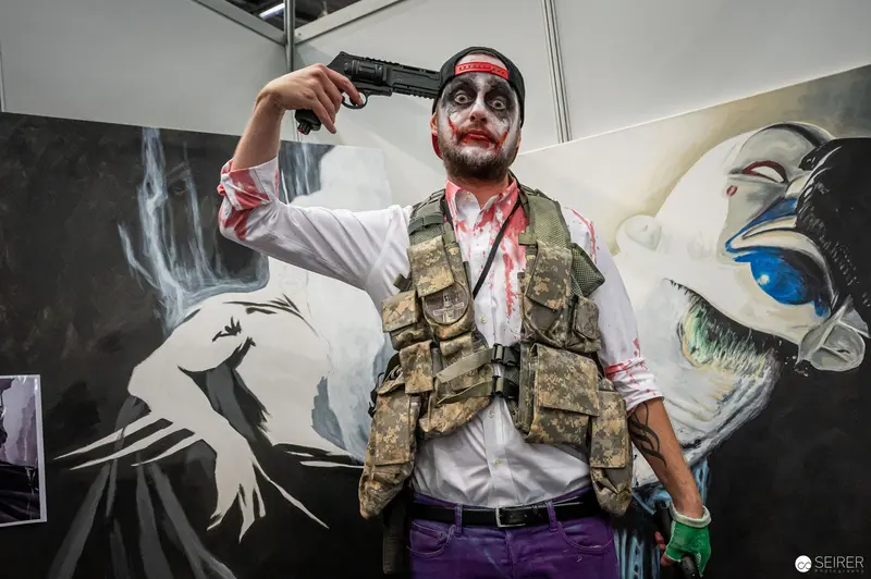 Bloodied Cosplayer with Pistol at Vienna ComicCon Poses Dramatically Against Artistic Backdrop