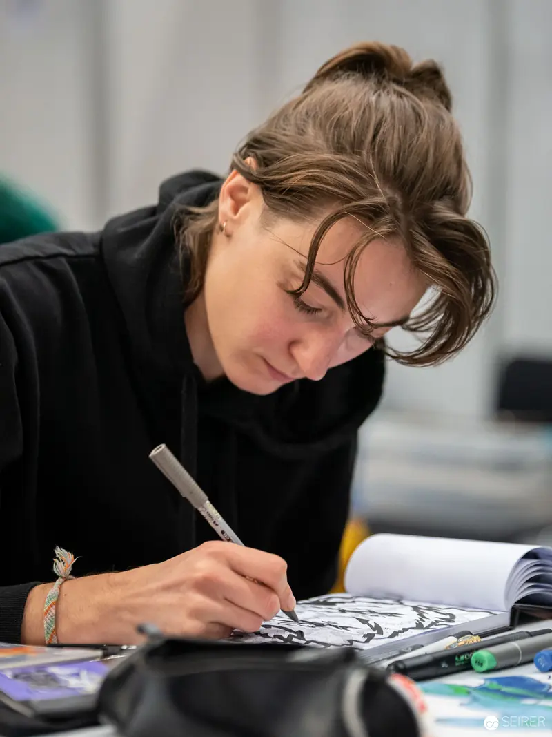 Artist Intently Drawing at Vienna ComicCon, Focused Creative Moment