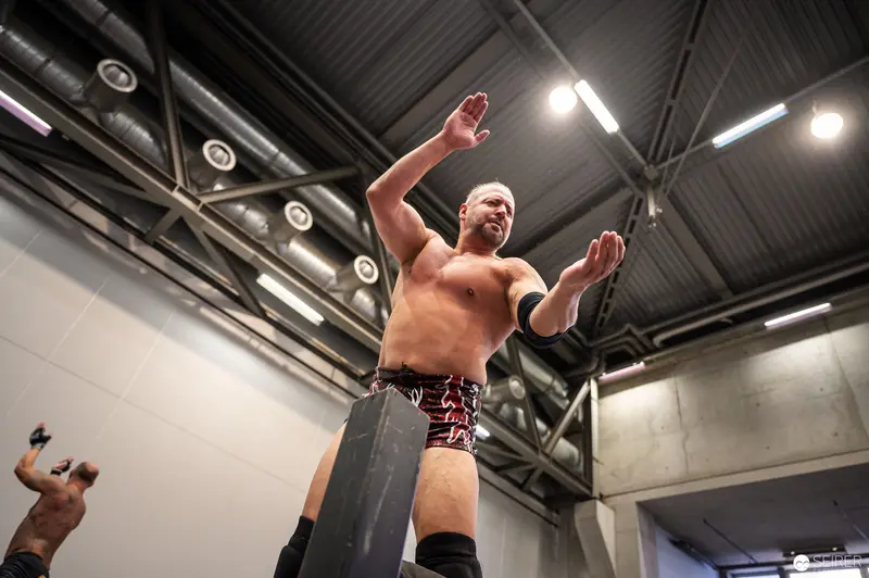 Professional Wrestler Raises Arms in Industrial Performance Space at VIECC 2022