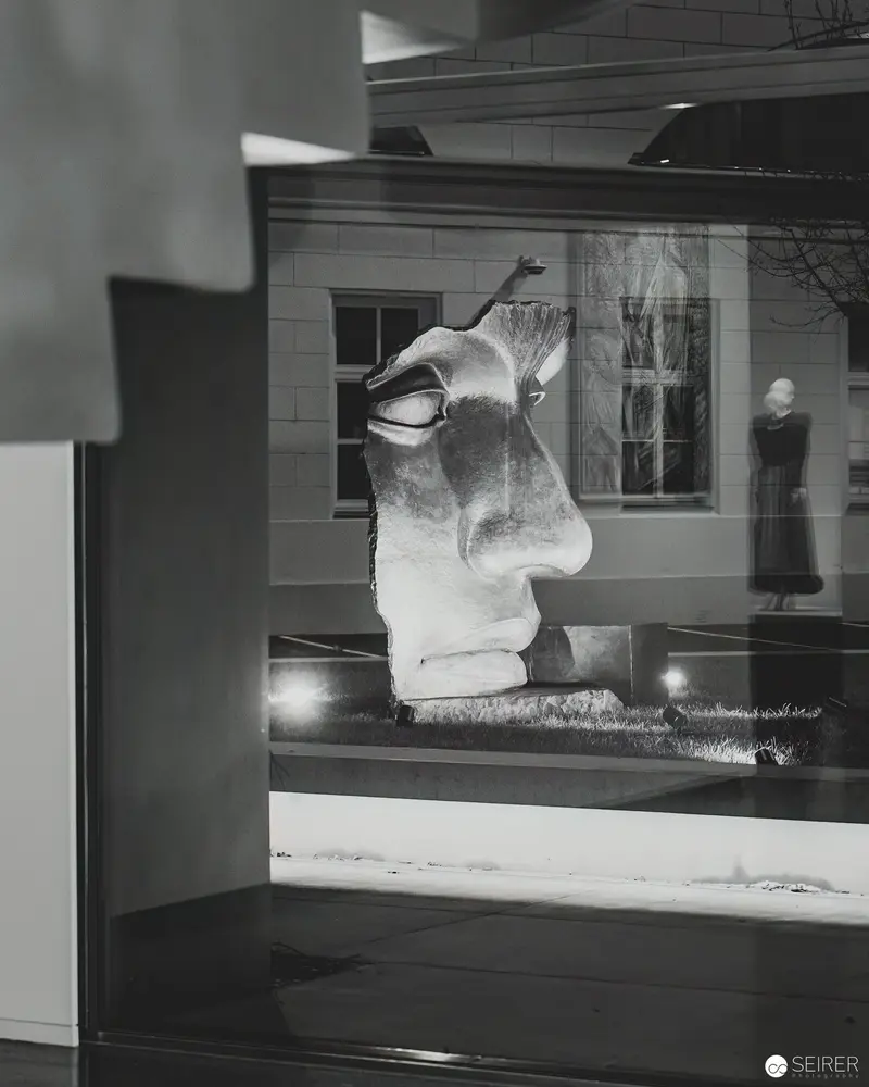 Sculptural Fragment in Gallery Window Reflecting Interior Exhibition Space