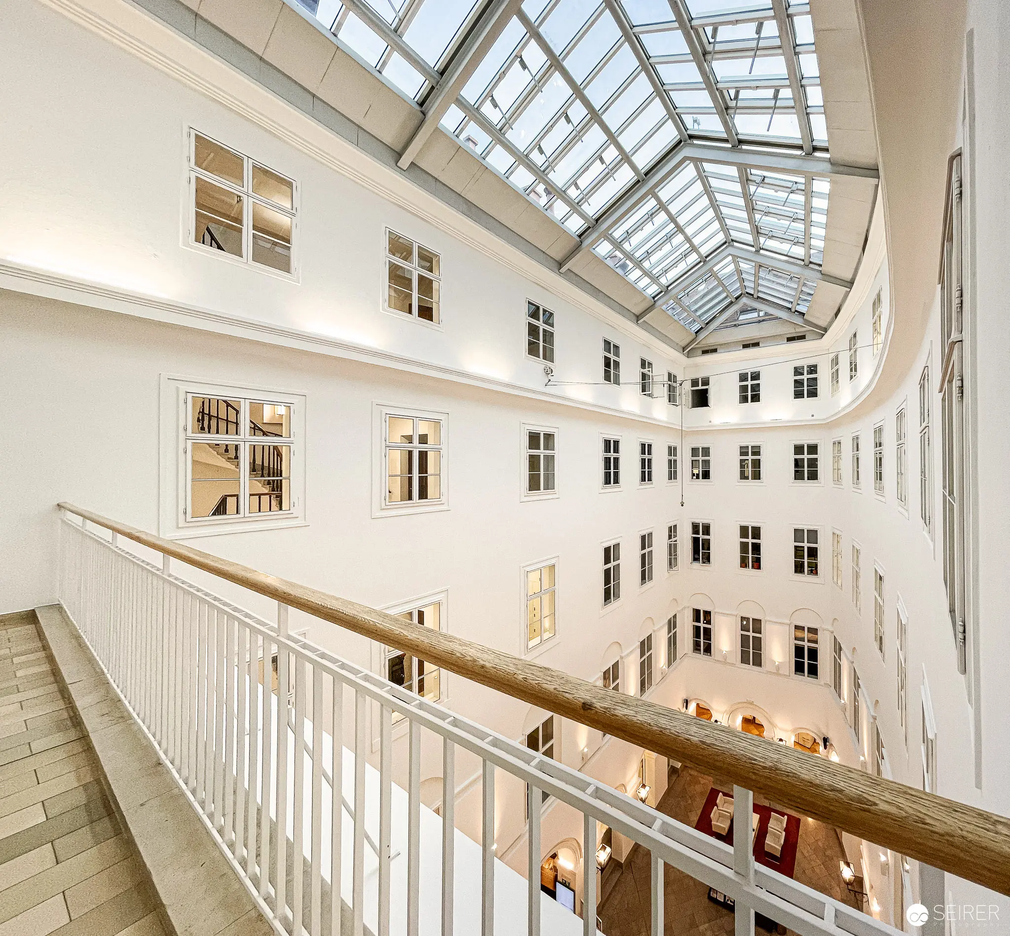 Webster University Vienna Interior: Luminous Atrium with Glass Skylight and Curved Architecture