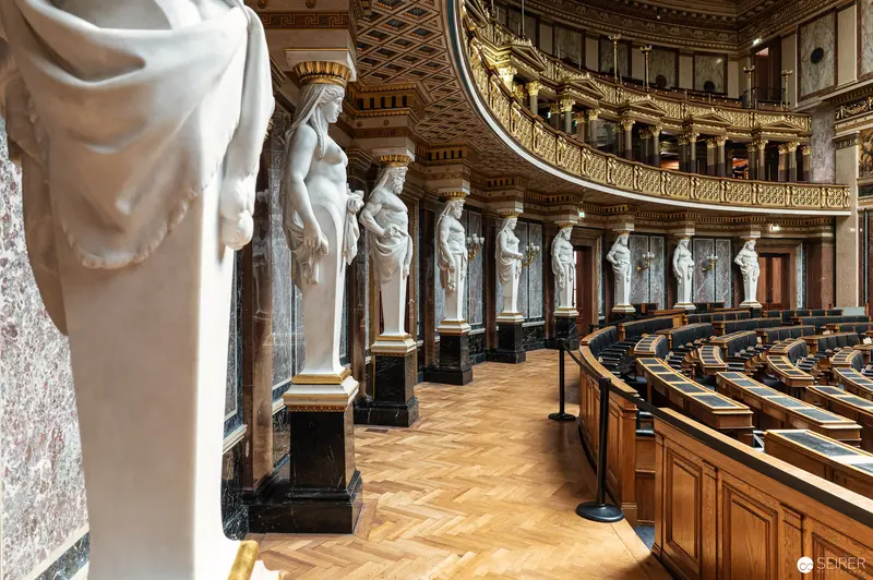 Neoclassical Interior of Vienna Parliament with Marble Statues and Curved Seating
