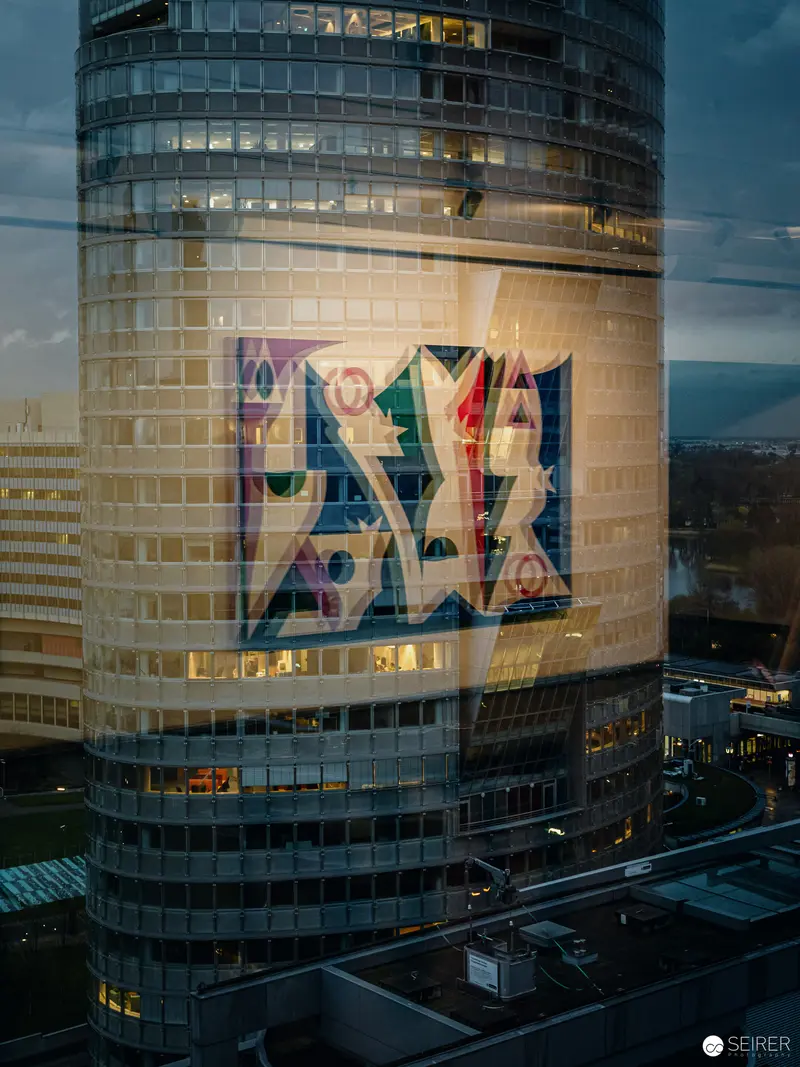 Illuminated Corporate Logo on Curved Glass Skyscraper at Twilight