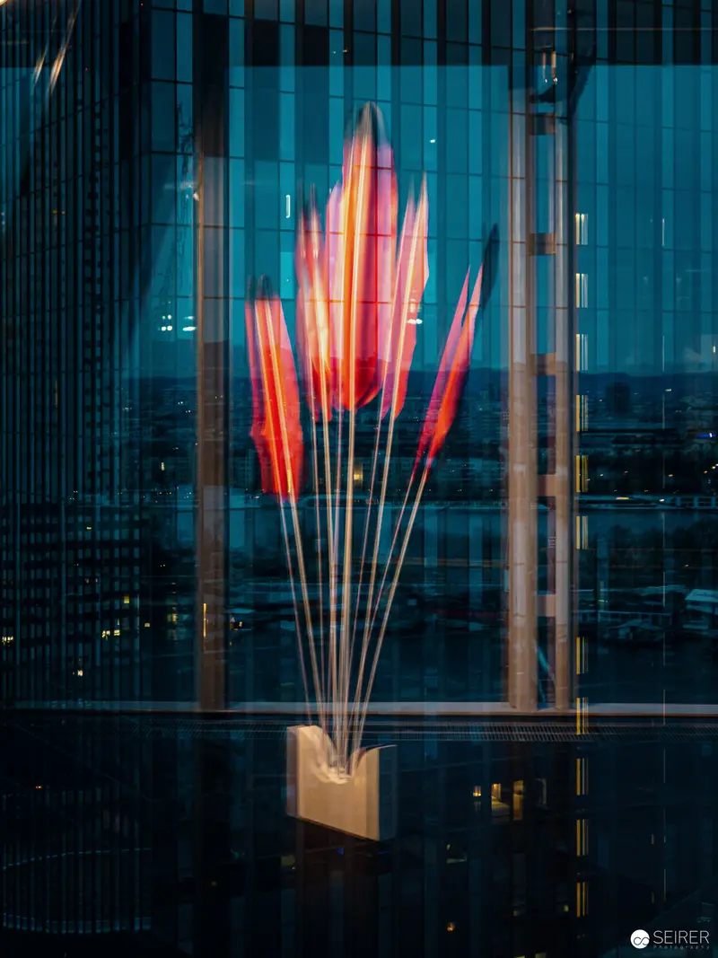 Luminous Red Sculptural Form Against Urban Architectural Grid