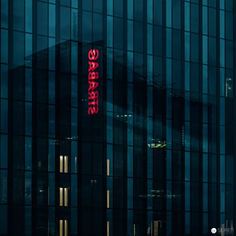 Illuminated Strabag Kunstforum Facade with Vertical Glowing Red Typography