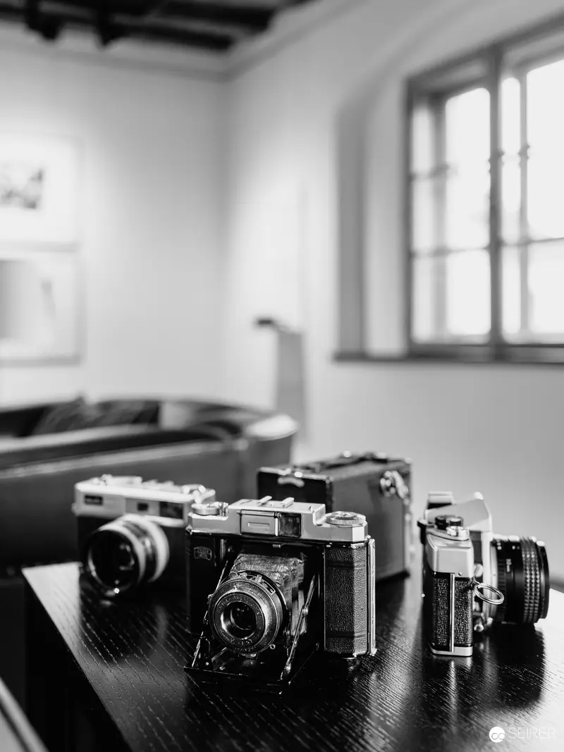 Vintage Analog Cameras Arranged on Dark Wooden Surface in Monochrome