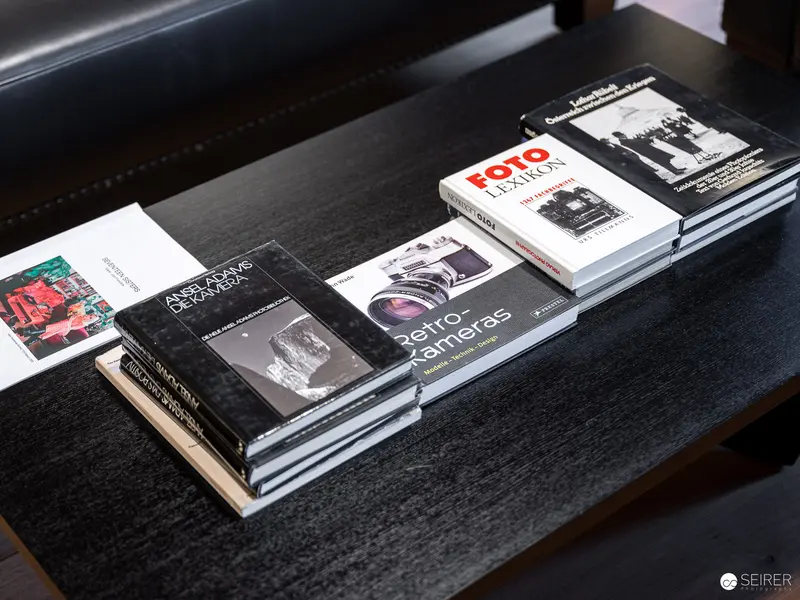 Photography Books Arranged on Dark Wooden Surface at Exhibition Venue