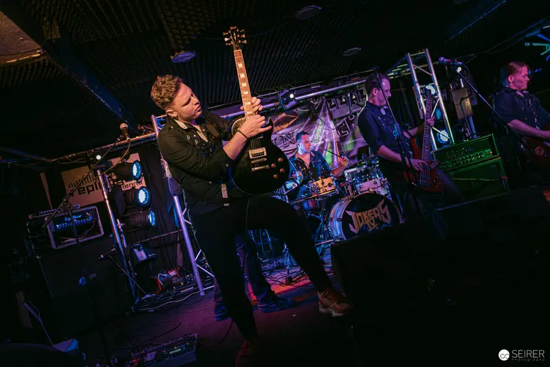 Erin Performing at Replugged Venue with Electric Guitar Under Dramatic Lighting