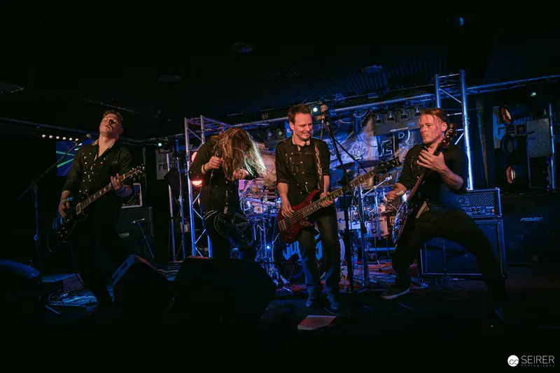 Replugged Rock Band Performing Intense Set at Vienna Venue Under Blue Stage Lights