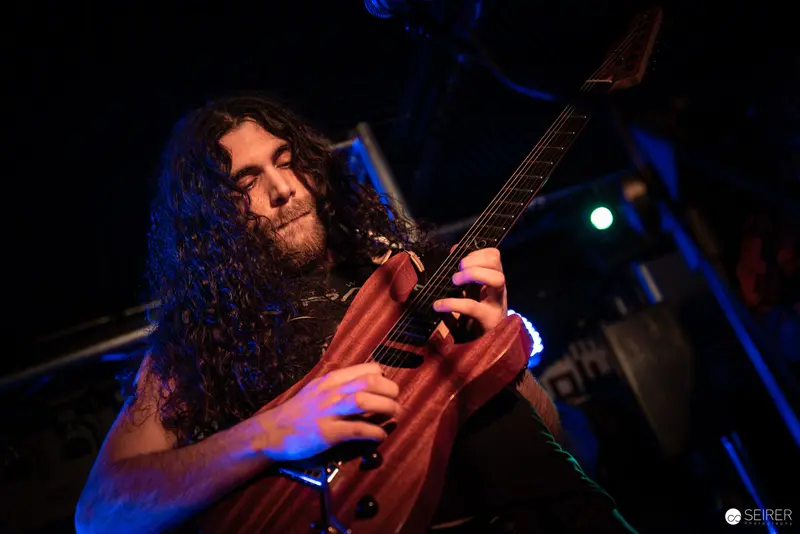 Extreme Mind Guitarist Performing Intensely Under Colored Stage Lighting at Replugged