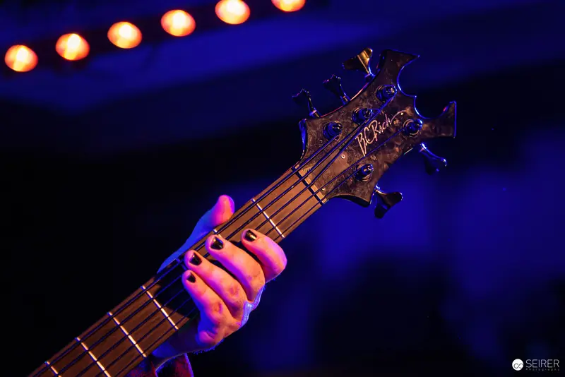 Nightmarcher Bass Guitarist's Hand at Replugged Vienna Concert in Vivid Blue Lighting