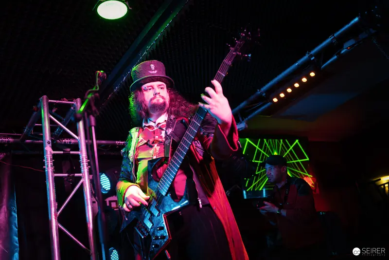 Nightmarcher Guitarist Performing Energetically at Replugged Vienna with Vibrant Stage Lighting