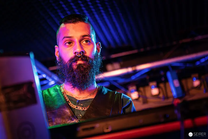 Nightmarcher at Replugged Vienna: Bearded Performer Illuminated by Colorful Stage Lights