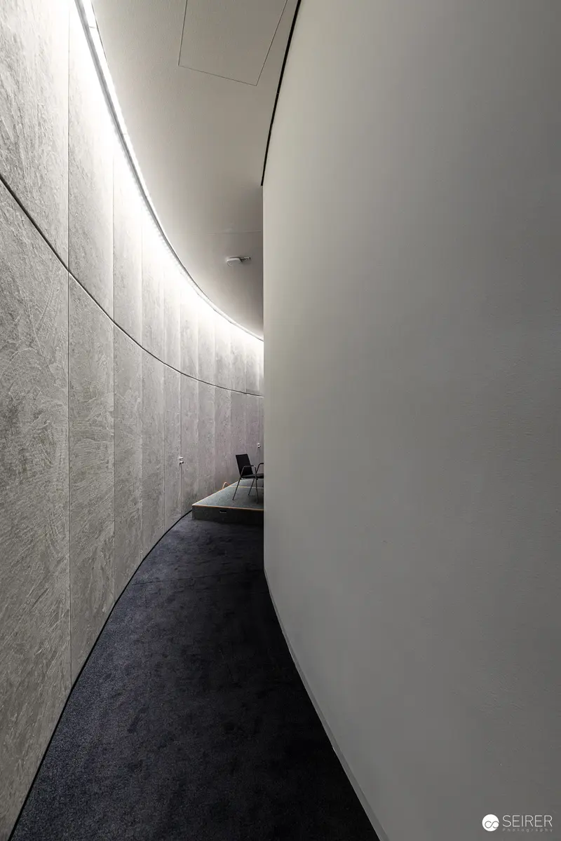 Minimalist Architectural Interior with Curved Wall and Dark Carpeted Corridor
