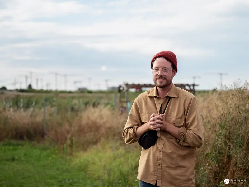 Urban Farmer in Red Beanie Surveys Sustainable Agricultural Landscape