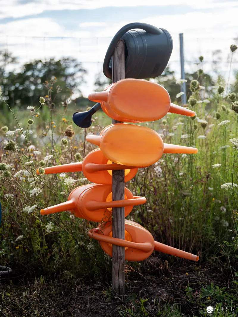 Sculptural Orange Playground Seats Nestled in Wild Meadow Vegetation