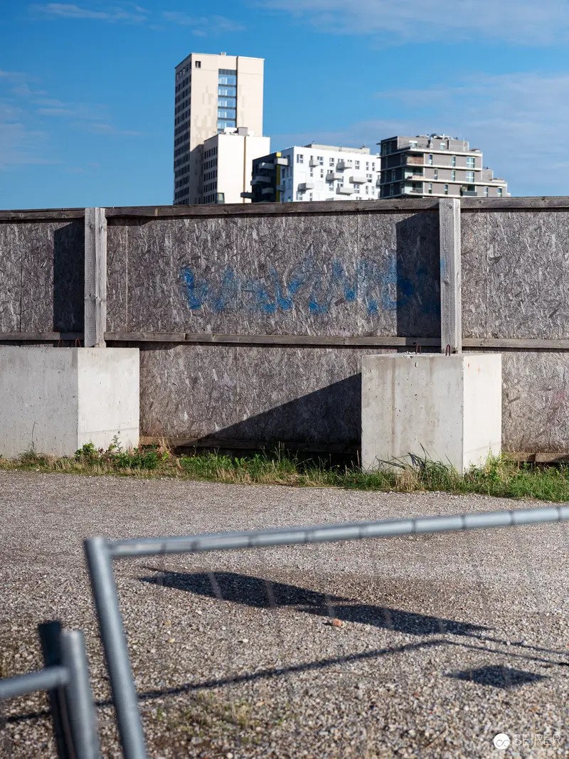 Urban Architectural Fragment with Concrete Wall and Distant High-Rise Buildings