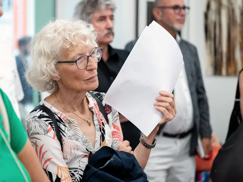 Elderly Woman Examining Document at Cultural Event or Exhibition