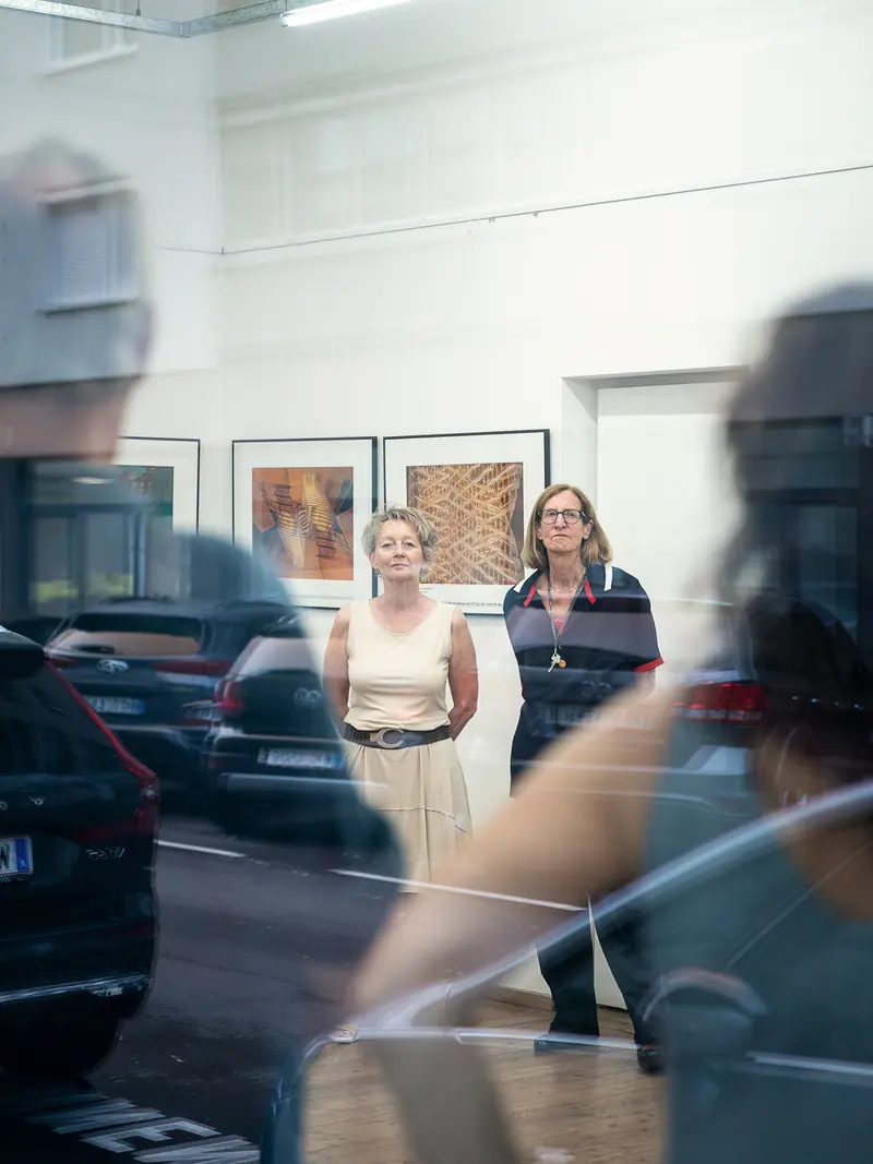 Interior Reflection: Two Women Framed by Automotive Glass and Gallery Space