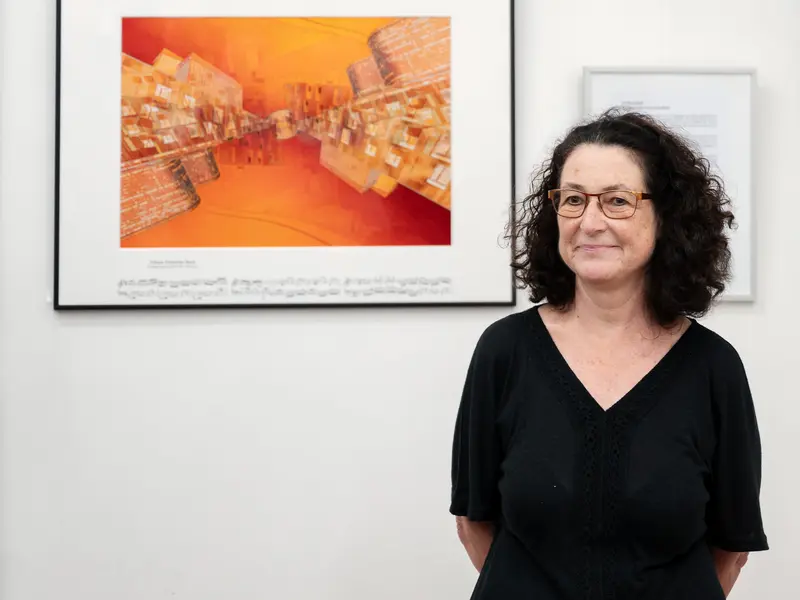 Gallery Curator Standing Beside Contemporary Orange-Toned Abstract Wall Art