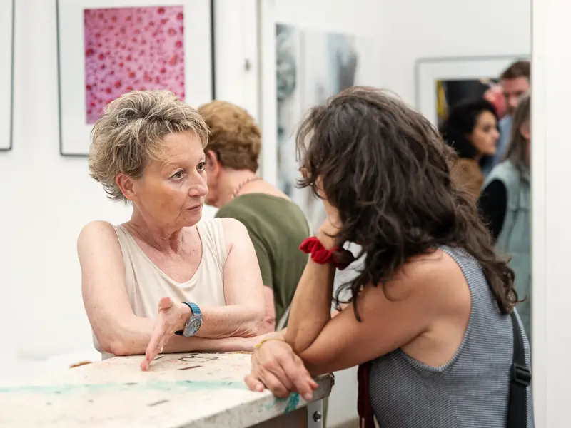 Two Women in Conversation at Gallery Exhibition Opening