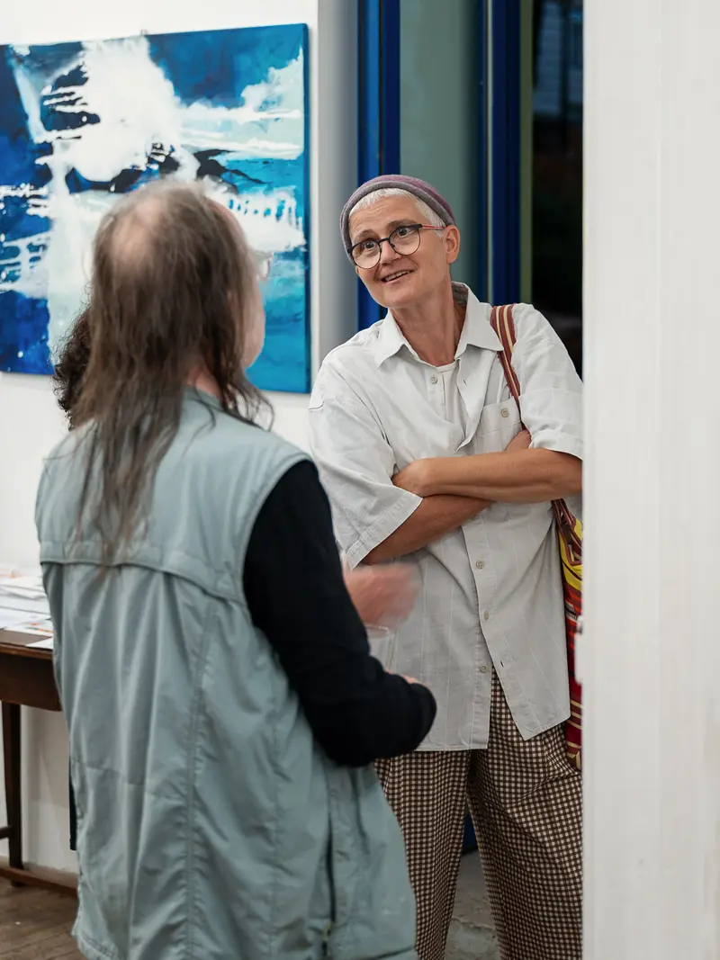 Two Gallery Visitors Conversing Near Abstract Blue Artwork