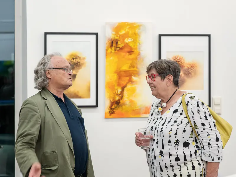 Gallery Visitors Discuss Vibrant Yellow Abstract Artwork During Exhibition