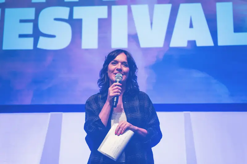Speaker Presenting at Health & Mind Festival Under Blue-Tinted Stage Lighting