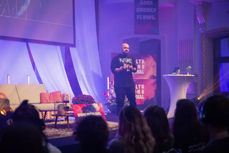 Speaker Presenting at Health & Mind Festival Under Dramatic Purple Lighting