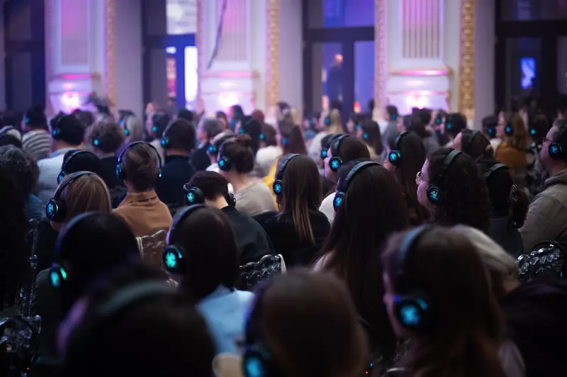 Health & Mind Festival: Silent Audience in Blue-Lit Auditorium with Wireless Headphones