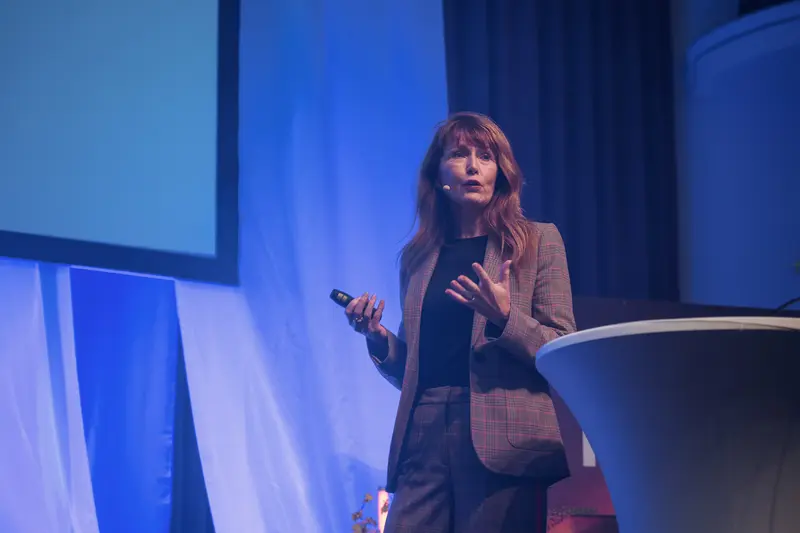 Health & Mind Festival Speaker Delivers Keynote on Blue-Lit Conference Stage
